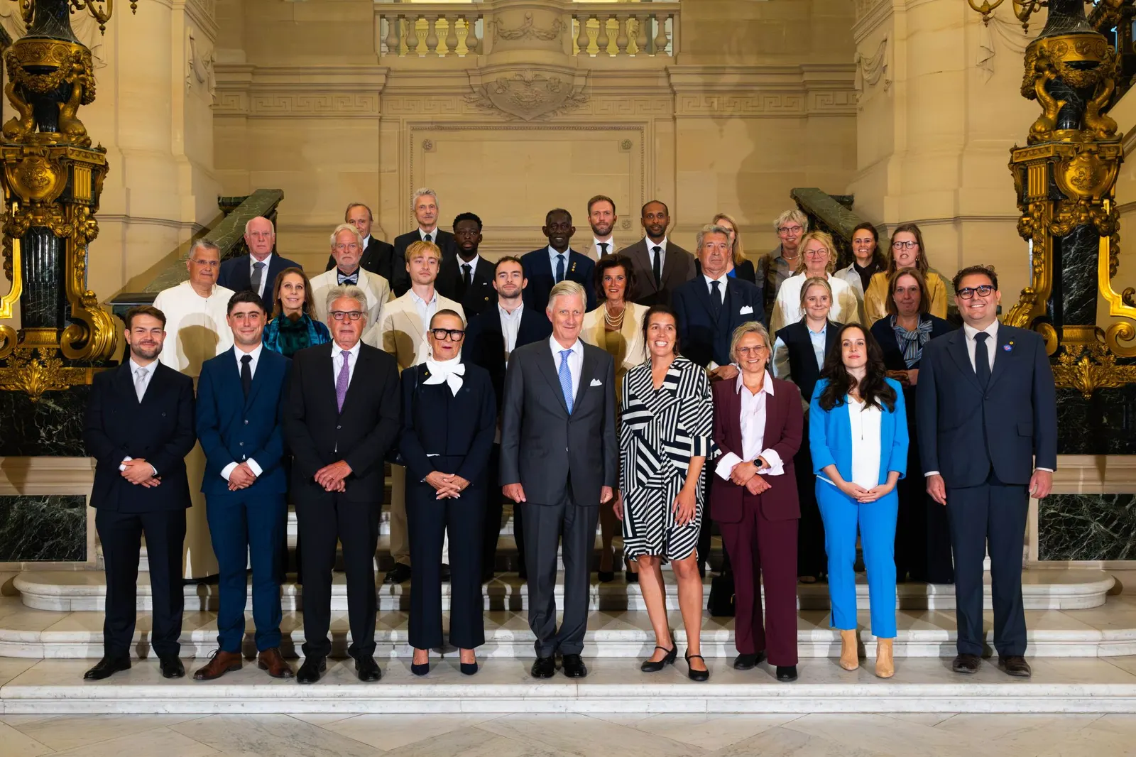 Groepsfoto van de twaalf BeHeroes met koning Filip op de trap van het Koninklijk Paleis