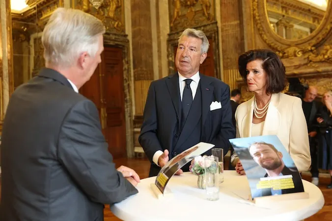 Koning Filip tegenover Patrick en Donatienne, aan een statafel in het Koninklijk Paleis