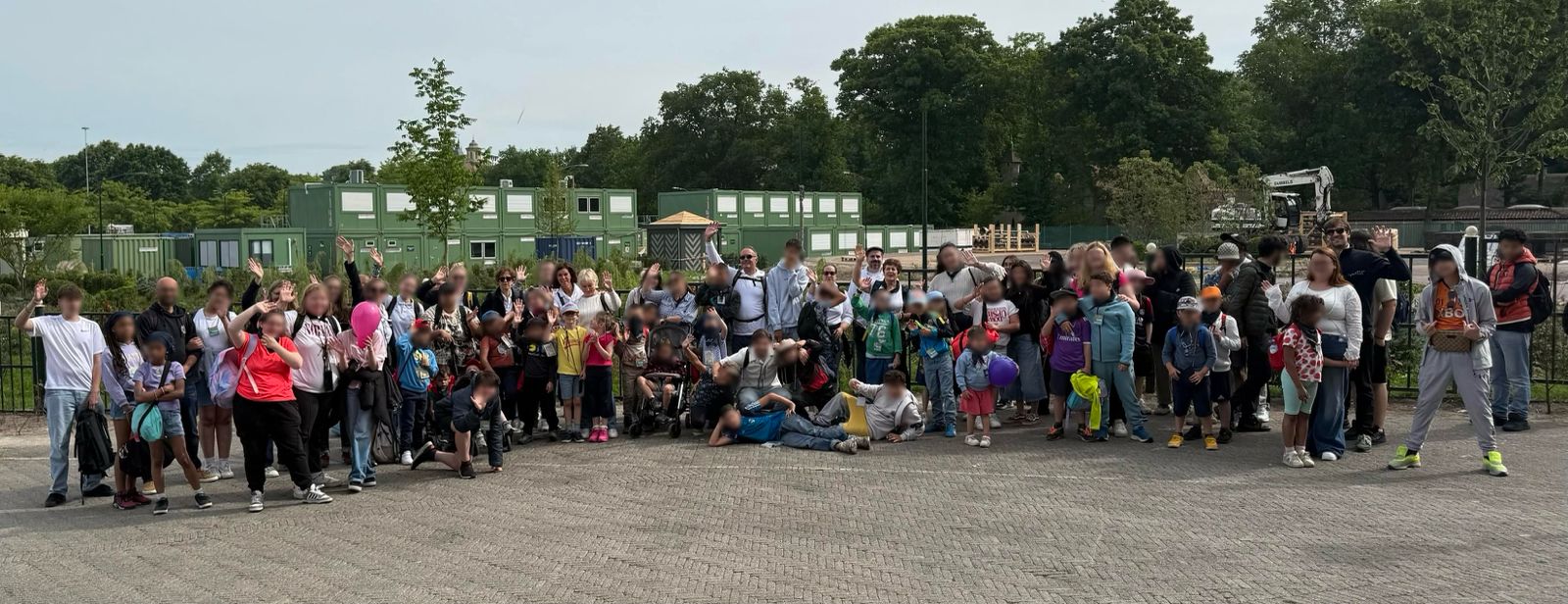 Een groep kinderen en volwassenen poseert buiten.